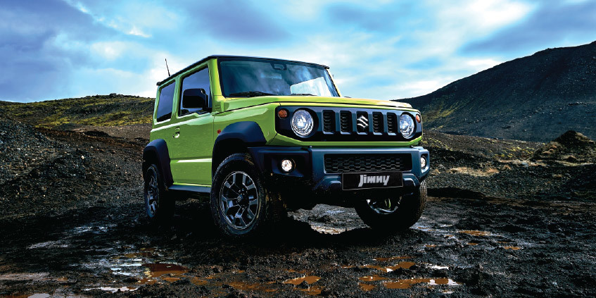 Jimny verde de Suzuki, un vehículo todoterreno compacto, posado en un terreno rocoso.