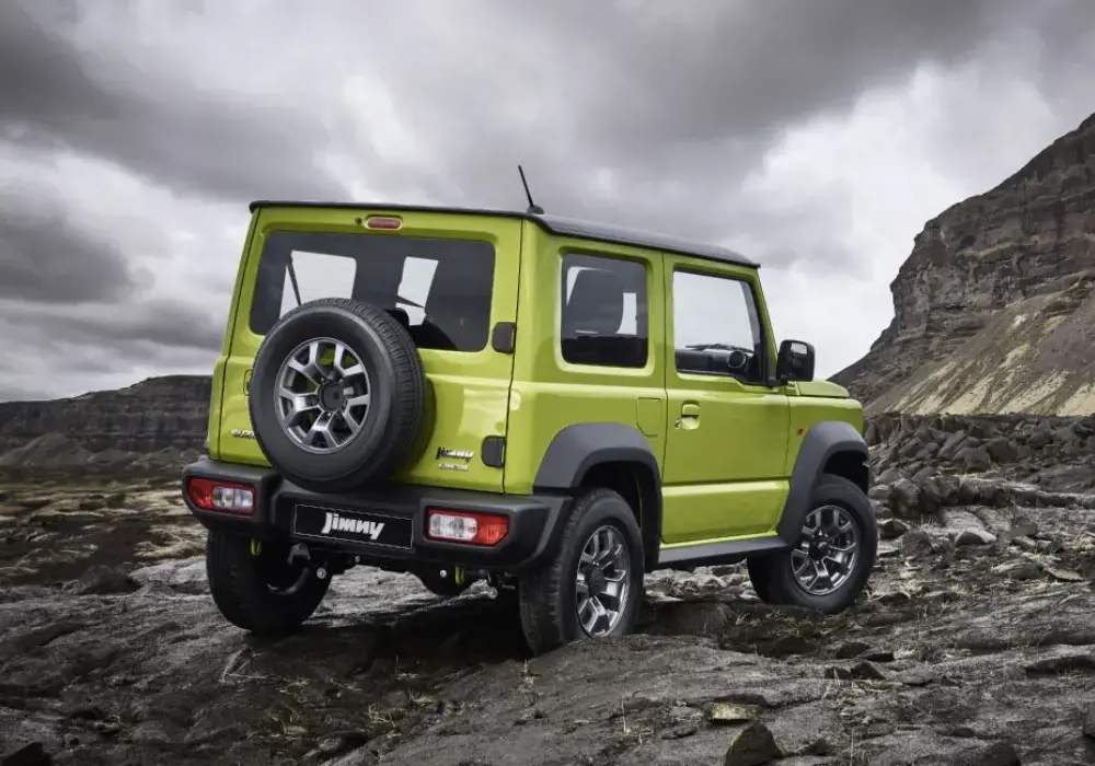 Vista trasera de un Suzuki Jimny color verde lima estacionado en un terreno rocoso
