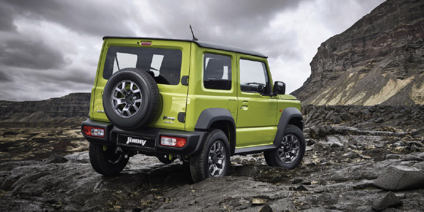 Suzuki Jimny verde, un 4x4 compacto, visto desde atrás en un paisaje rocoso.